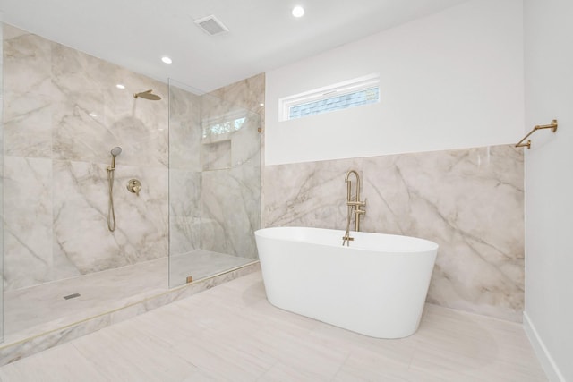 bathroom with recessed lighting, a marble finish shower, a freestanding bath, and visible vents