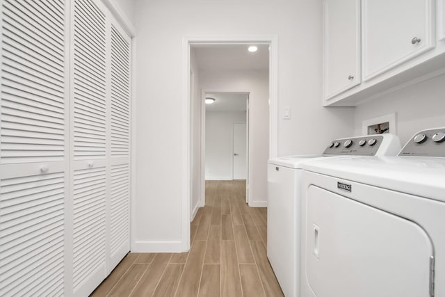 laundry area featuring cabinet space, baseboards, wood tiled floor, and separate washer and dryer