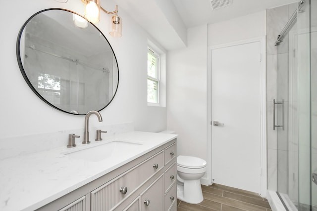 bathroom with vanity, visible vents, wood tiled floor, a shower stall, and toilet