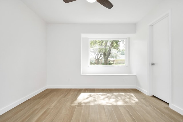 empty room featuring a ceiling fan, baseboards, and light wood finished floors