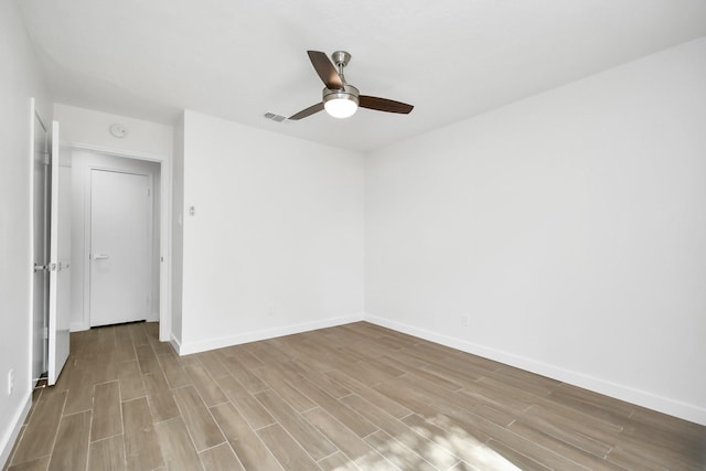 unfurnished room featuring a ceiling fan, wood finished floors, visible vents, and baseboards