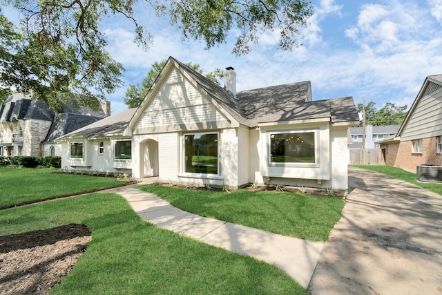 view of front of home featuring central AC, fence, a front yard, brick siding, and a chimney