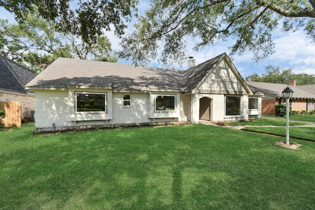 view of front of home featuring brick siding, a chimney, and a front lawn