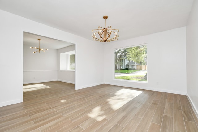 unfurnished room featuring a notable chandelier, light wood-style floors, and baseboards