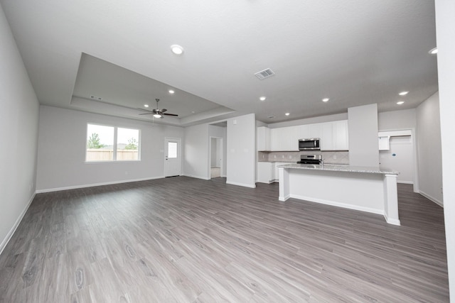 16527 Willow Forest Dr, Conroe, TX 77302 - unfurnished living room with baseboards, a ceiling fan, a raised ceiling, light wood finished floors, and recessed lighting