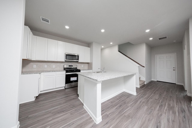 16527 Willow Forest Dr, Conroe, TX 77302 - kitchen with appliances with stainless steel finishes, a sink, light wood-style floors, white cabinetry, and light stone counters