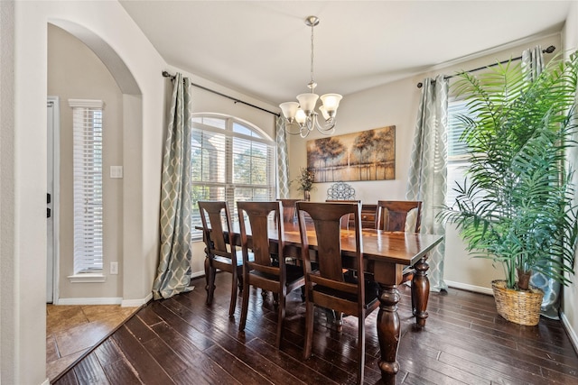 dining room featuring baseboards, arched walkways, a chandelier, and hardwood / wood-style flooring