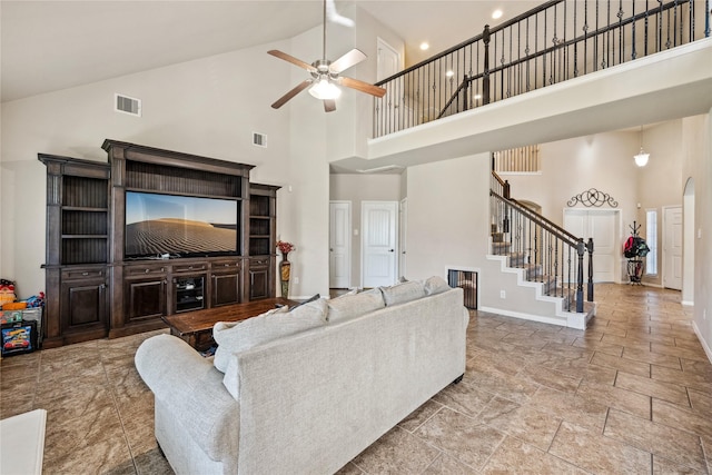 living room with stairway, baseboards, visible vents, a high ceiling, and ceiling fan