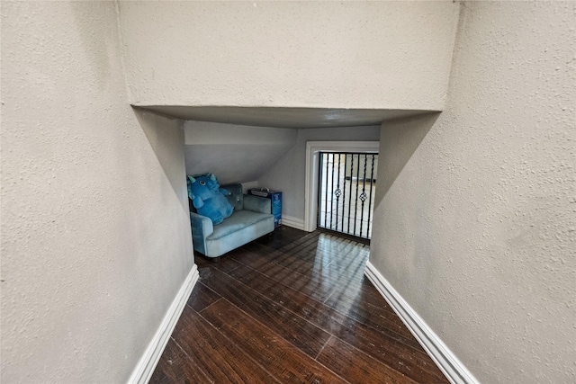 hallway featuring baseboards, hardwood / wood-style floors, and a textured wall