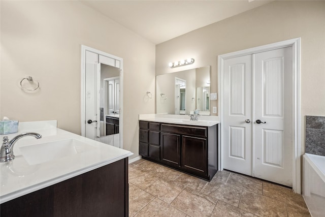 bathroom featuring a sink, a tub, and two vanities