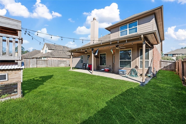 back of property with a yard, a fenced backyard, a chimney, ceiling fan, and a patio area