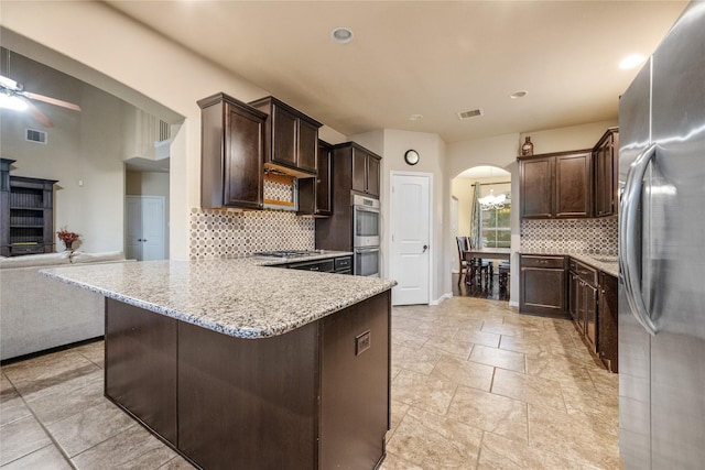 kitchen with arched walkways, dark brown cabinetry, appliances with stainless steel finishes, and visible vents