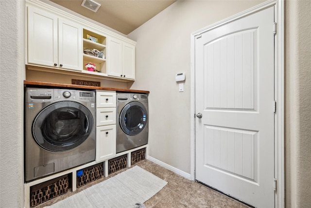 laundry area featuring washer and clothes dryer, visible vents, cabinet space, and baseboards