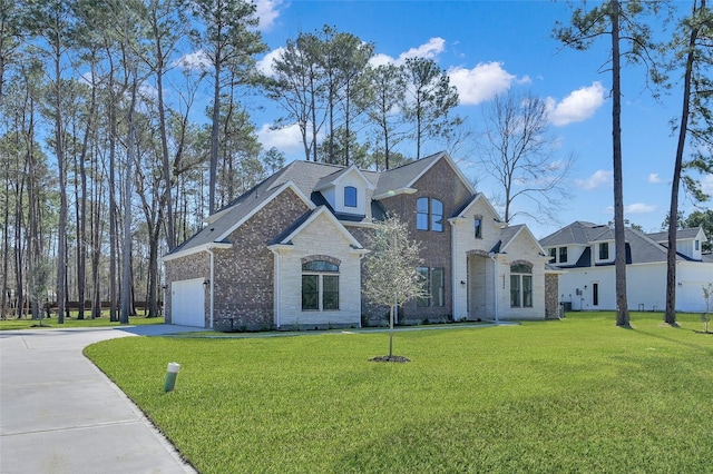 french country home with brick siding, driveway, and a front lawn