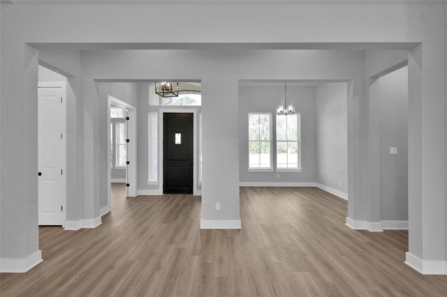 foyer entrance with baseboards, wood finished floors, and a chandelier