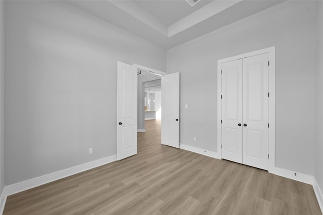 unfurnished bedroom with a closet, baseboards, and light wood-style flooring