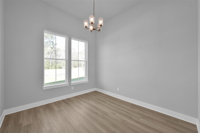 empty room with baseboards, an inviting chandelier, and wood finished floors