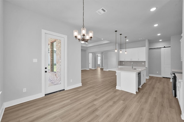 kitchen with a sink, open floor plan, a barn door, light countertops, and decorative backsplash