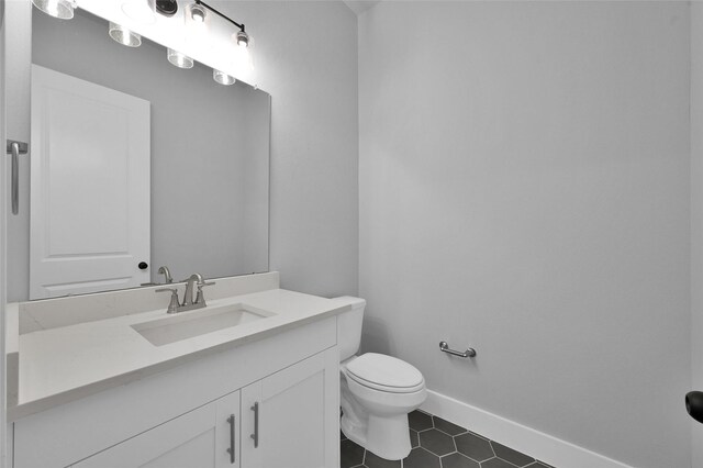 bathroom with vanity, toilet, baseboards, and tile patterned flooring