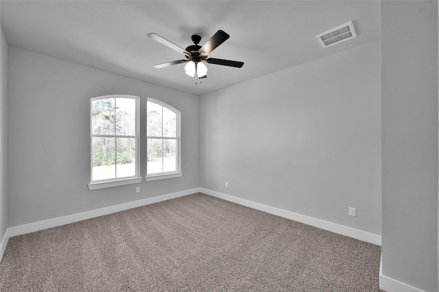 carpeted empty room featuring visible vents, ceiling fan, and baseboards