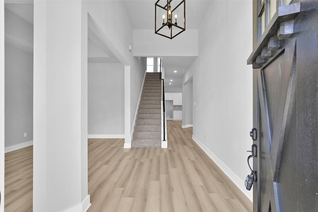 entryway with a high ceiling, stairway, baseboards, and light wood finished floors