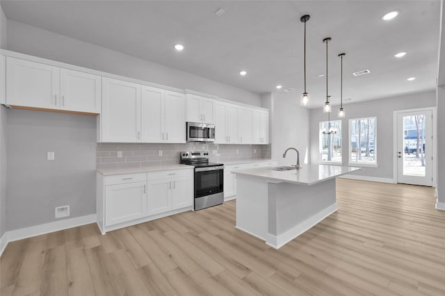 kitchen featuring a sink, tasteful backsplash, white cabinetry, stainless steel appliances, and light countertops