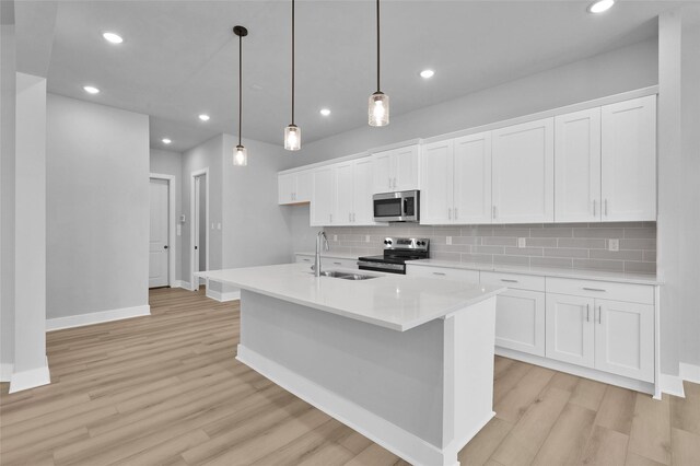 kitchen featuring tasteful backsplash, light wood-type flooring, appliances with stainless steel finishes, white cabinets, and a sink