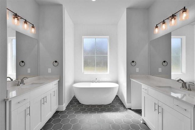 full bathroom featuring tile patterned floors, a freestanding bath, two vanities, and a sink