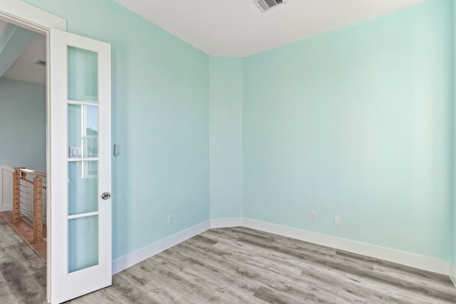 spare room with visible vents, baseboards, and wood finished floors