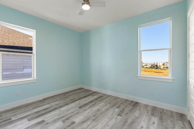 spare room with a healthy amount of sunlight, baseboards, and wood finished floors