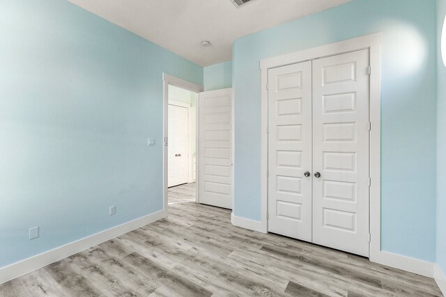 unfurnished bedroom with a closet, baseboards, and wood finished floors