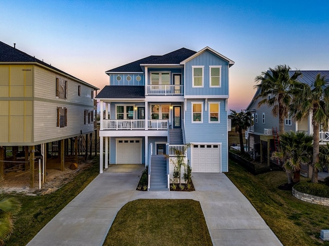 beach home with board and batten siding, a front lawn, concrete driveway, stairs, and a balcony