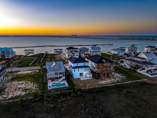 aerial view at dusk with a residential view and a water view