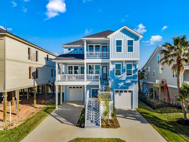 beach home with a balcony, stairway, driveway, an attached garage, and board and batten siding