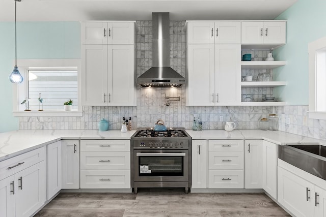 kitchen featuring decorative backsplash, white cabinets, stainless steel range, wall chimney exhaust hood, and open shelves