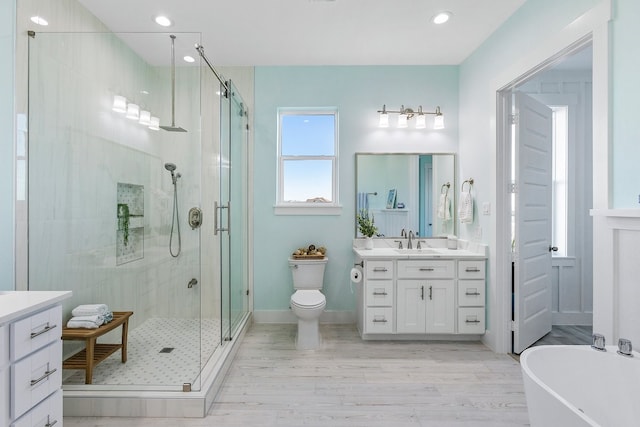 bathroom featuring a freestanding tub, toilet, a stall shower, and vanity