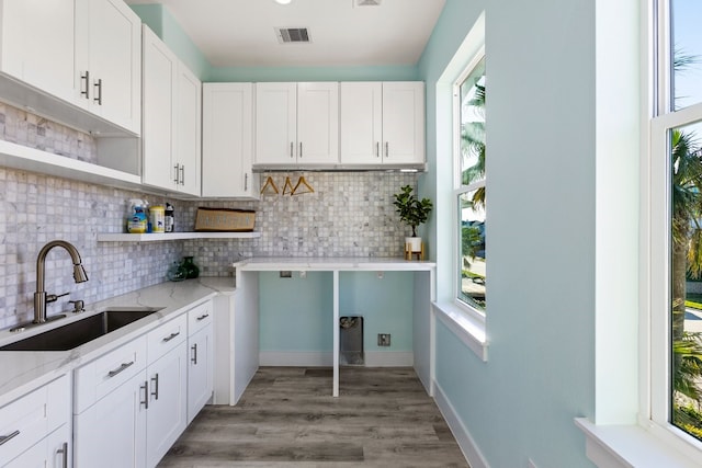 kitchen with light stone counters, visible vents, open shelves, a sink, and white cabinets