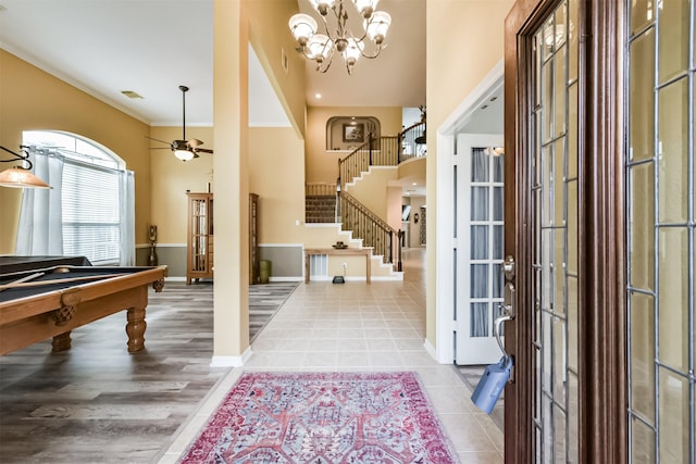 tiled foyer with visible vents, baseboards, stairs, ceiling fan with notable chandelier, and billiards