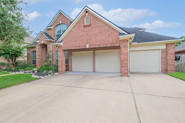 traditional-style home featuring brick siding, a garage, concrete driveway, and roof with shingles