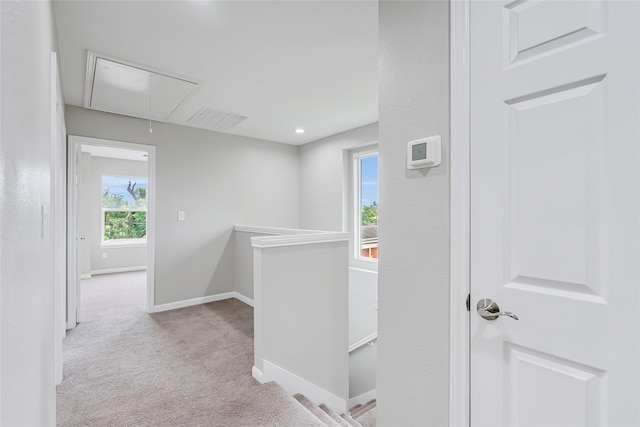 hall featuring visible vents, an upstairs landing, carpet flooring, baseboards, and attic access