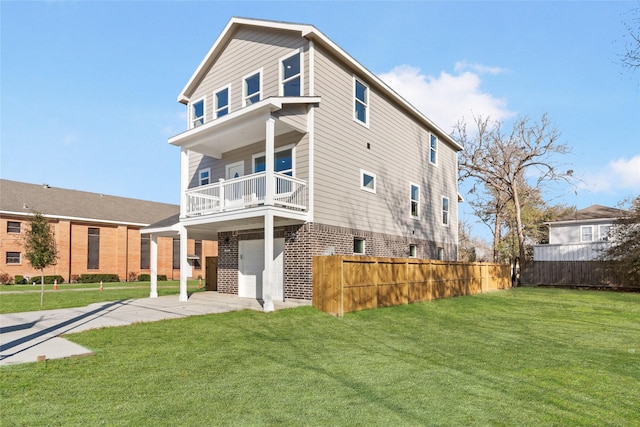 back of house with a balcony, fence, driveway, a lawn, and brick siding