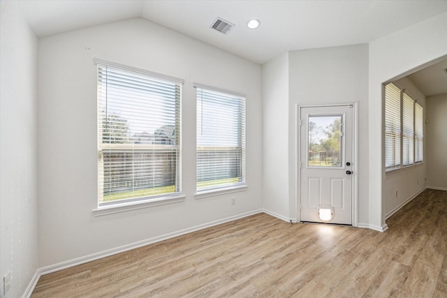 entrance foyer with light wood finished floors, visible vents, baseboards, vaulted ceiling, and arched walkways