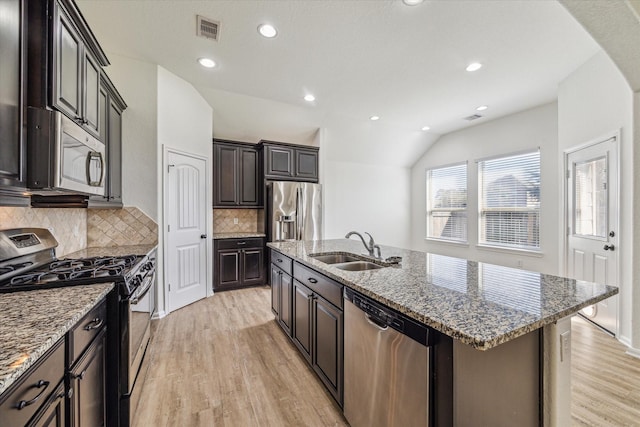 kitchen featuring visible vents, light wood-style flooring, an island with sink, a sink, and appliances with stainless steel finishes