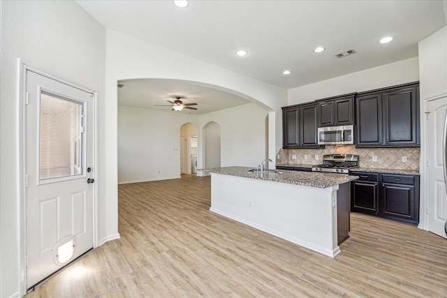 kitchen with visible vents, arched walkways, light wood-style floors, and appliances with stainless steel finishes