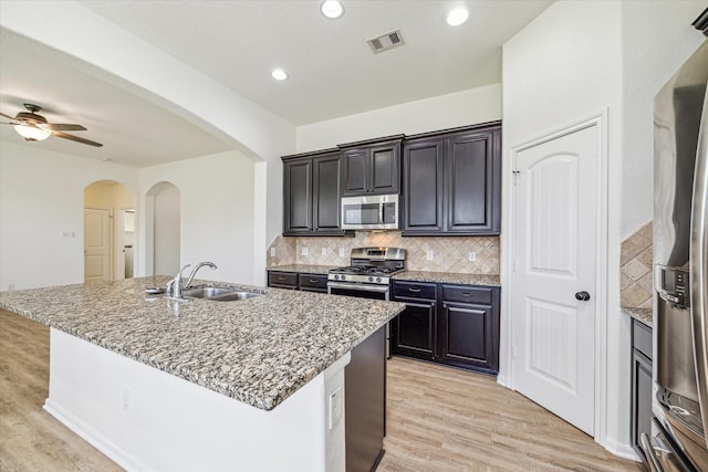 kitchen with visible vents, a sink, appliances with stainless steel finishes, light wood finished floors, and decorative backsplash