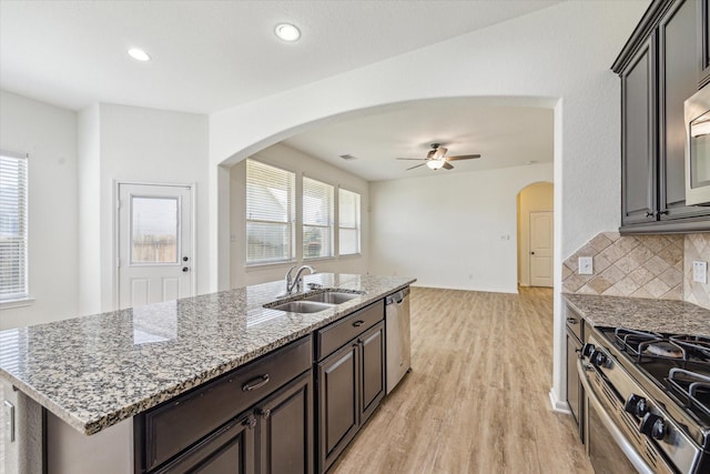 kitchen featuring arched walkways, decorative backsplash, appliances with stainless steel finishes, and a sink