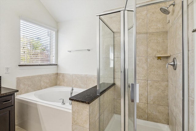 full bathroom with a stall shower, vanity, a garden tub, and vaulted ceiling