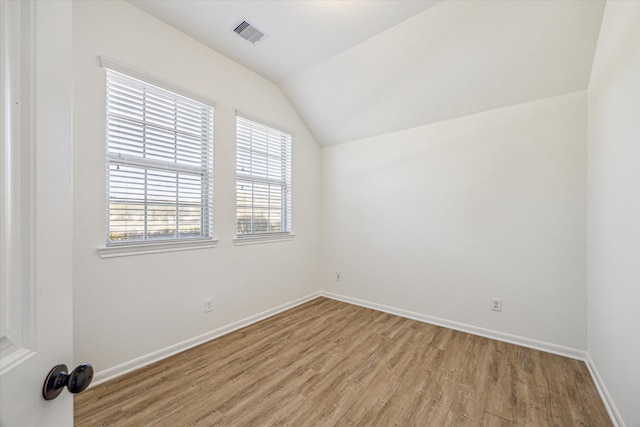 unfurnished room with visible vents, baseboards, light wood-style floors, and vaulted ceiling