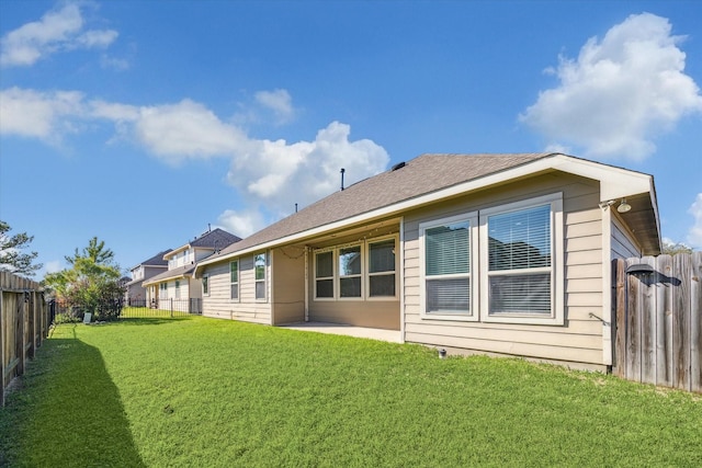 back of property with a fenced backyard, a patio, a yard, and roof with shingles