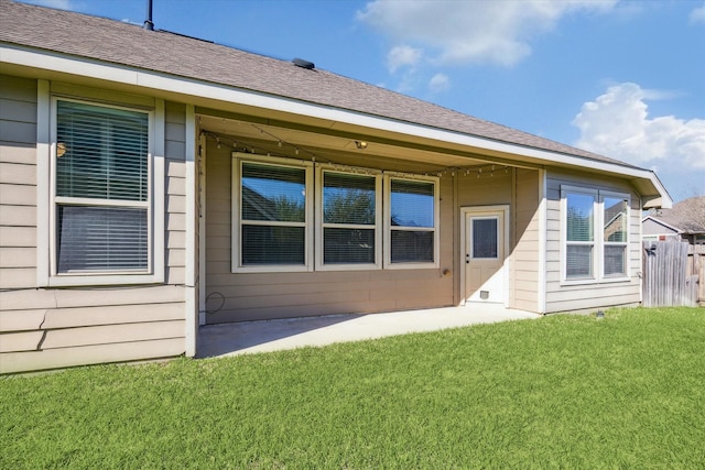 back of house with a yard, fence, and a shingled roof